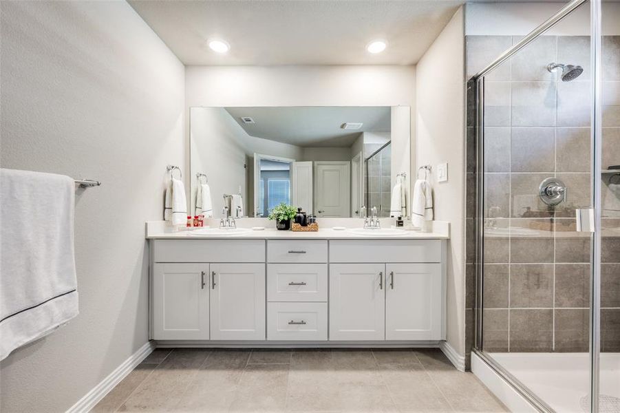 Full bathroom featuring a stall shower, double vanity, and light tile patterned floors Full bathroom featuring a stall shower, double vanity, and light tile patterned floors