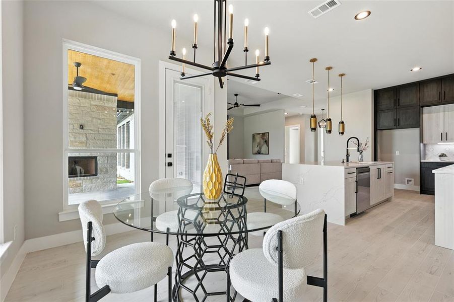 Dining space featuring a ceiling fan, light wood finished floors, recessed lighting, a chandelier, and a fireplace