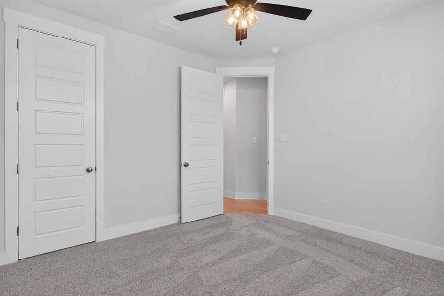 Neutral-toned room featuring a ceiling fan with integrated lighting, soft gray carpeting, and white baseboards Neutral-toned room featuring a ceiling fan with integrated lighting, soft gray carpeting, and white baseboards