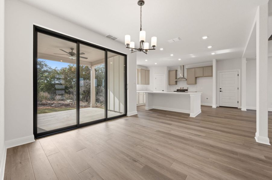 Spacious kitchen featuring built in microwave drawer, large center island, abundant storage, breakfast bar, eat-in kitchen dining area, modern style range hood, stainless appliances, and pantry