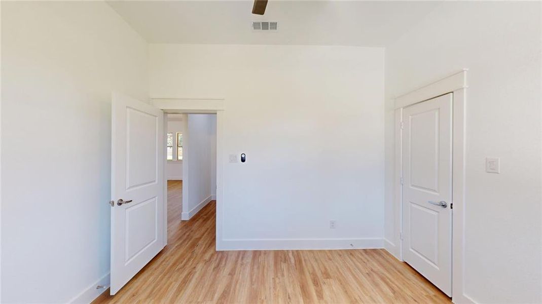 Spare room featuring light wood-style flooring, a ceiling fan, visible vents, and baseboards