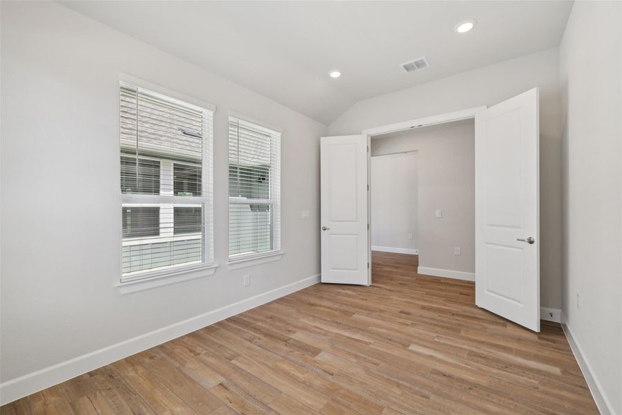 Unfurnished bedroom featuring light wood-style floors, recessed lighting, and lofted ceiling