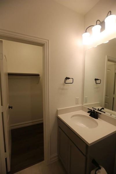 Bathroom vanity featuring a single basin sink, matte black faucet, and a light-colored countertop