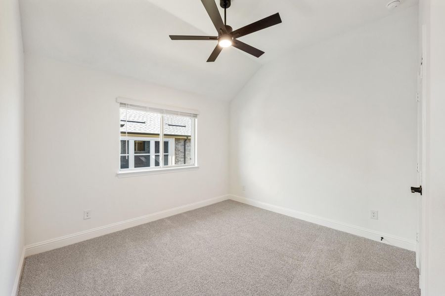 Empty bedroom with vaulted ceiling, ceiling fan, carpet flooring, and single window Empty bedroom with vaulted ceiling, ceiling fan, carpet flooring, and single window