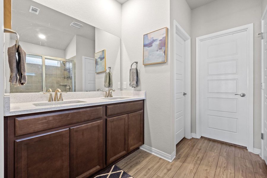 Bathroom with double vanity, a shower stall, and light wood-style flooring Bathroom with double vanity, a shower stall, and light wood-style flooring
