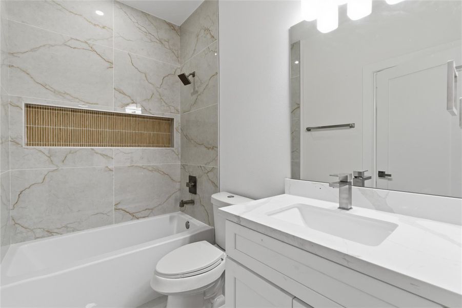 A well-appointed third-floor bath connects the bedroom and flex space, featuring a quartz vanity and a tiled tub/shower combo with modern finishes.