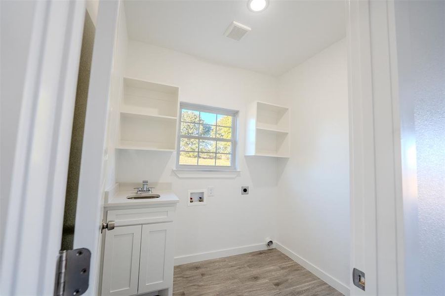 Laundry area featuring light wood-type flooring, hookup for an electric dryer, and hookup for a washing machine Laundry area featuring light wood-type flooring, hookup for an electric dryer, and hookup for a washing machine