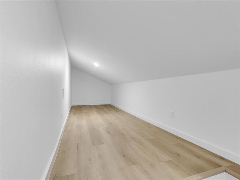 Bonus room with vaulted ceiling and light hardwood / wood-style flooring