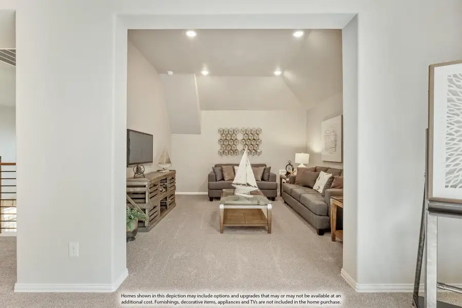 Living room with vaulted ceiling, gray sofas, carpet flooring, and recessed lighting viewed through a wide doorway. Living room with vaulted ceiling, gray sofas, carpet flooring, and recessed lighting viewed through a wide doorway.