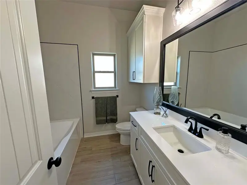 Bathroom with a bath, vanity, and light wood-style flooring Bathroom with a bath, vanity, and light wood-style flooring