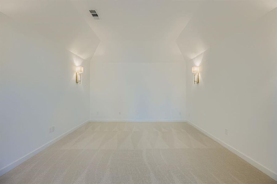 Additional living space featuring light carpet and vaulted ceiling