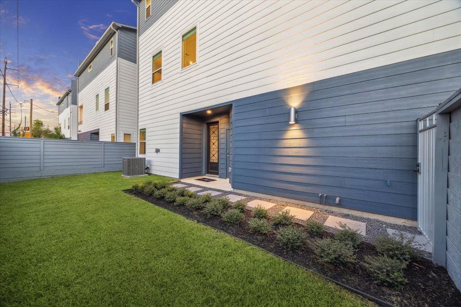 This contemporary residence showcases a well-designed side yard that is connected to the main entrance, offering a seamless blend of indoor and outdoor space. Ideal for relaxation or entertainment, the yard is surrounded by clean landscaping and modern exterior lighting.