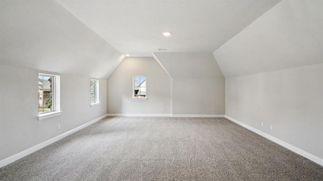 Bonus room featuring vaulted ceiling and carpet Bonus room featuring vaulted ceiling and carpet