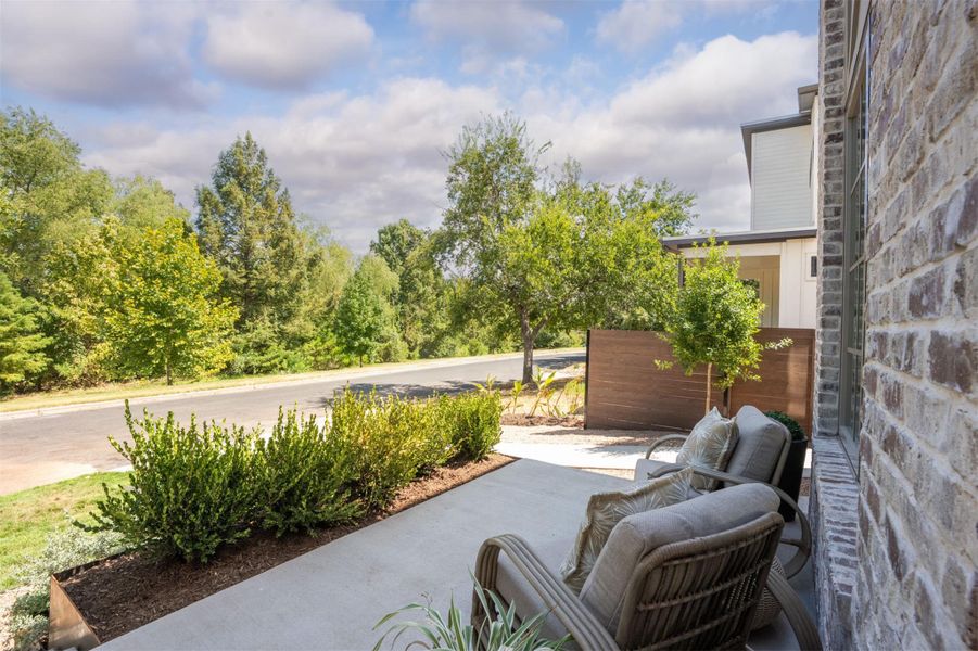 An inviting concrete patio overlooks a quiet street lined with mature green trees. An inviting concrete patio overlooks a quiet street lined with mature green trees.