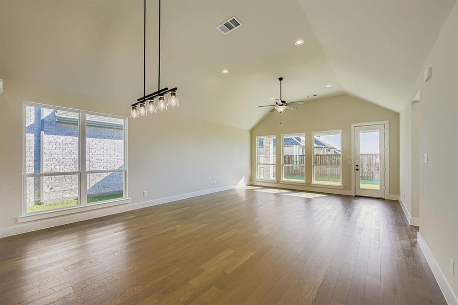 Unfurnished living room with recessed lighting, light wood finished floors, vaulted ceiling, and a ceiling fan Unfurnished living room with recessed lighting, light wood finished floors, vaulted ceiling, and a ceiling fan