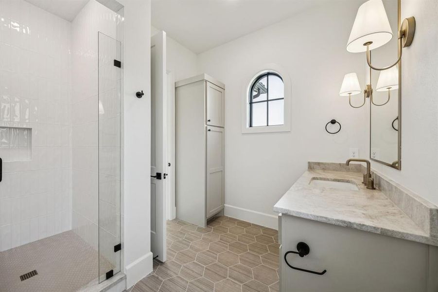 Bathroom featuring tiled shower, double vanity, and tile patterned floors Bathroom featuring tiled shower, double vanity, and tile patterned floors