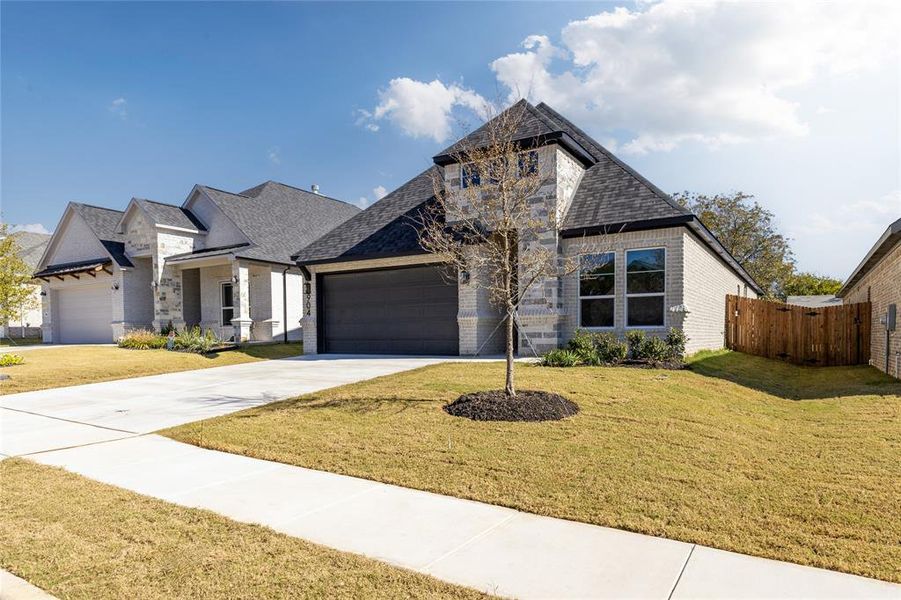 French provincial home featuring brick siding, driveway, a garage, and roof with shingles
