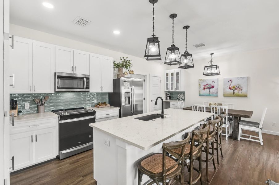 Kitchen with backsplash, a kitchen bar, appliances with stainless steel finishes, light stone countertops, and recessed lighting Kitchen with backsplash, a kitchen bar, appliances with stainless steel finishes, light stone countertops, and recessed lighting
