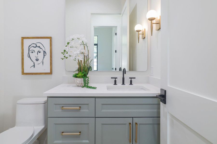 Modern bathroom vanity featuring light gray cabinetry with gold hardware, a white countertop, and an undermount sink