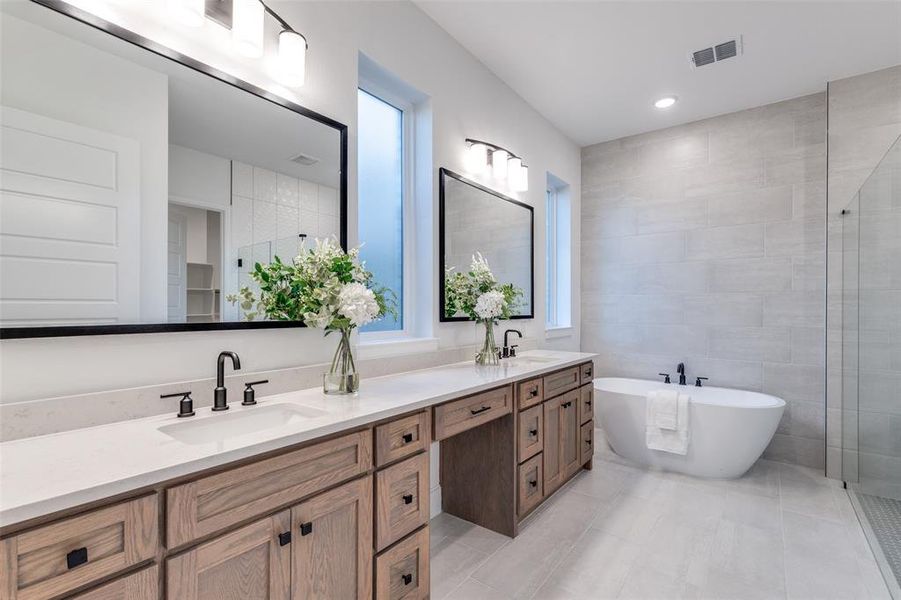 Spa-like primary bathroom with a freestanding bath, a large walk-in shower, double vanity, tile walls, and recessed lighting Spa-like primary bathroom with a freestanding bath, a large walk-in shower, double vanity, tile walls, and recessed lighting