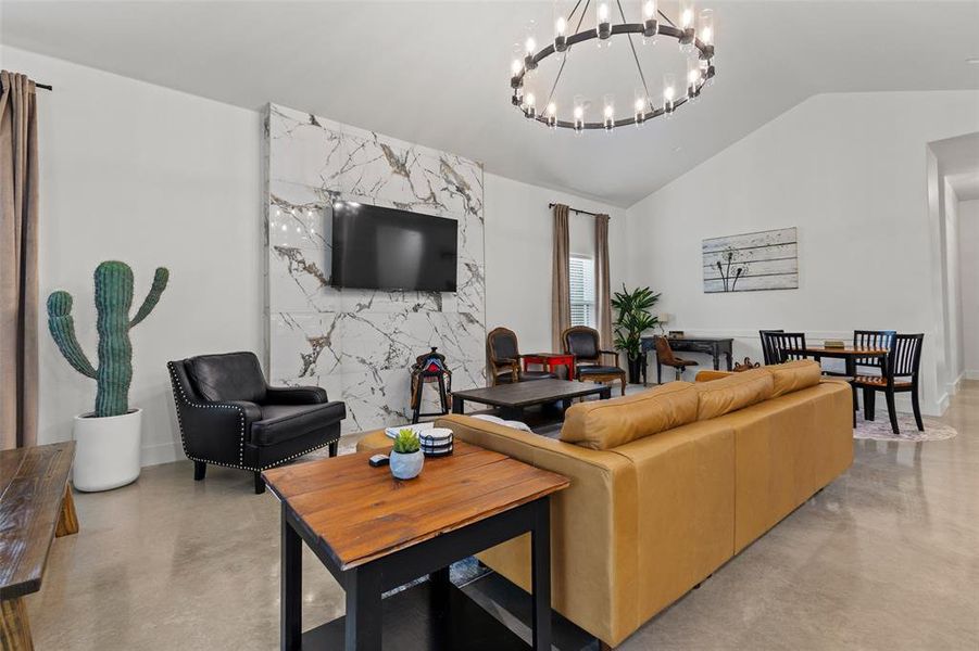 Living area with concrete floors, a chandelier, and vaulted ceiling