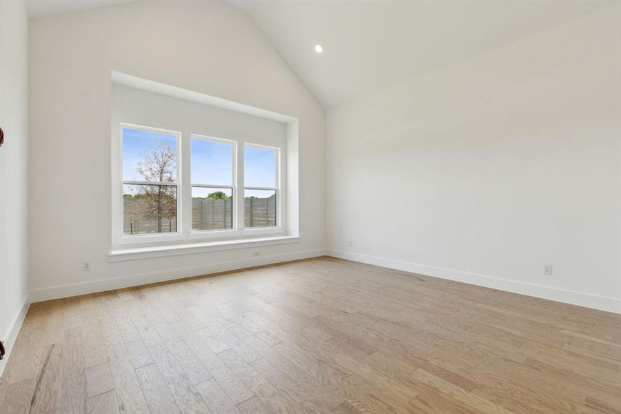 Vaulted ceiling room featuring three large windows, a deep window sill, wood-finish flooring, and recessed lighting Vaulted ceiling room featuring three large windows, a deep window sill, wood-finish flooring, and recessed lighting