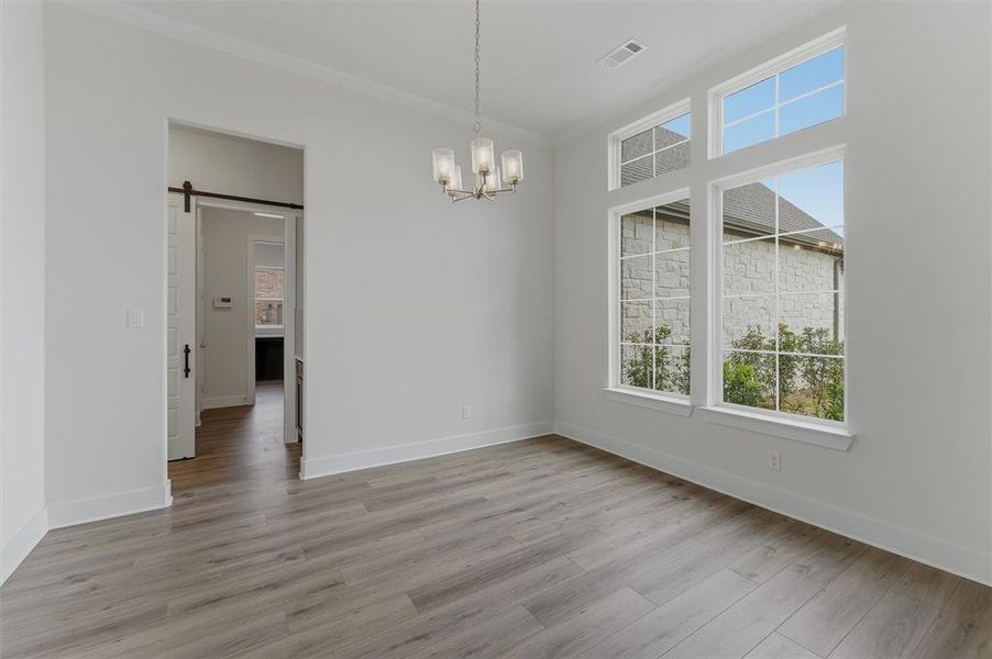 Expansive room featuring wood-finish flooring, white baseboards, and crown molding