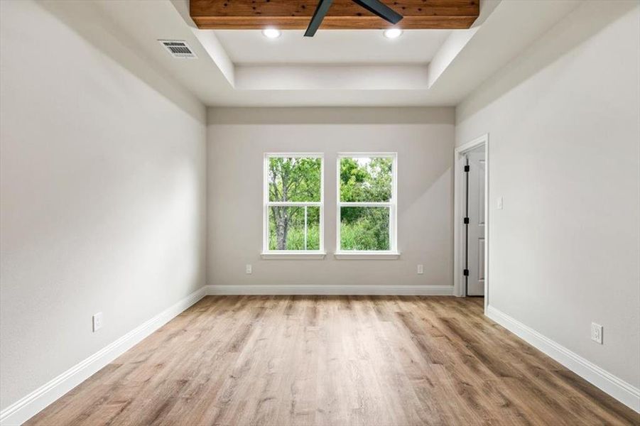 Recessed ceiling featuring a wood-finish beam and a contemporary ceiling fan