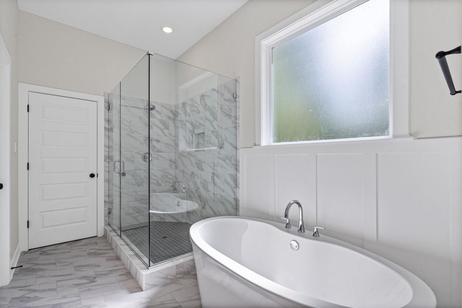 Full bath featuring a marble finish shower, a soaking tub, and light marble finish floors Full bath featuring a marble finish shower, a soaking tub, and light marble finish floors