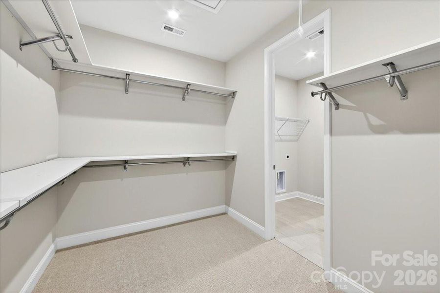 Primary walk-in closet with connection to the laundry room Primary walk-in closet with connection to the laundry room