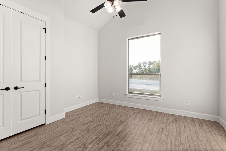 Unfurnished bedroom with vaulted ceiling, light wood finished floors, and ceiling fan Unfurnished bedroom with vaulted ceiling, light wood finished floors, and ceiling fan