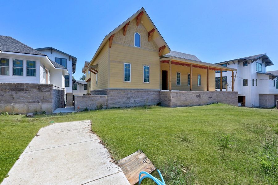 Back of house featuring a lawn and stone siding