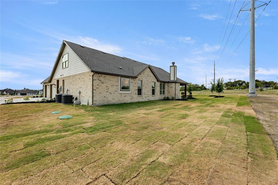View of side of home featuring brick siding, a yard, a shingled roof, and a chimney View of side of home featuring brick siding, a yard, a shingled roof, and a chimney