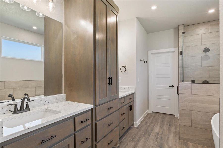 Bathroom featuring light wood-style flooring, vanity, a stall shower, recessed lighting, and a freestanding tub