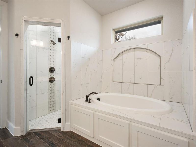 Bathroom with wood-type flooring and shower with separate bathtub