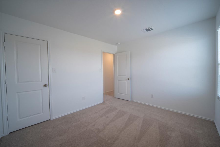 Unfurnished bedroom with light colored carpet and baseboards