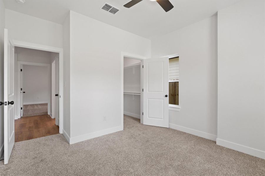 Carpeted room with white walls, a ceiling fan, and a window featuring horizontal blinds