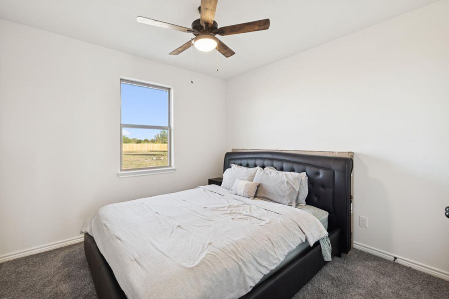 Carpeted bedroom featuring a ceiling fan and baseboards Carpeted bedroom featuring a ceiling fan and baseboards