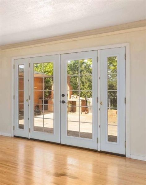 Doorway with wood finished floors, crown molding, and a textured ceiling