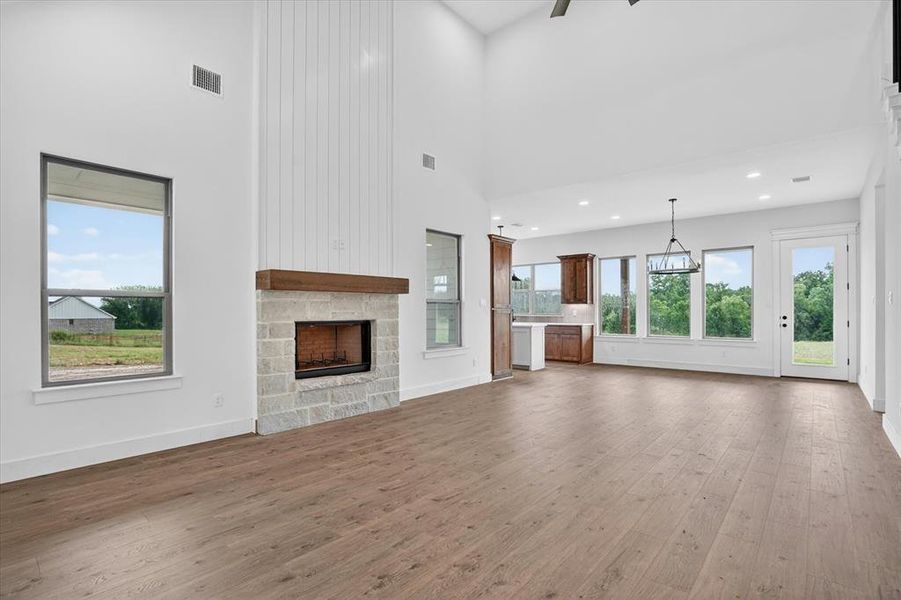 Spacious interior featuring a stone-faced fireplace with wood mantel, vaulted ceilings, and wood-finish flooring