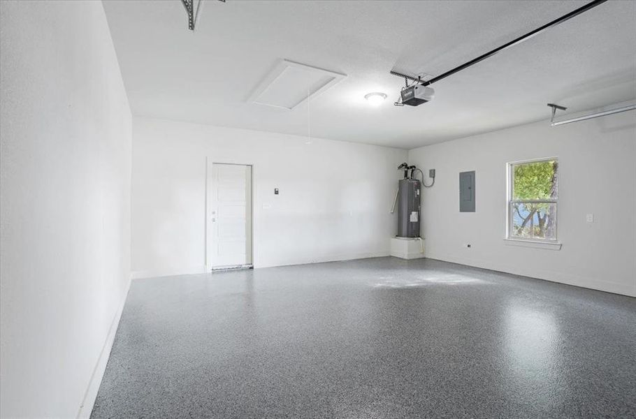 Garage with electric water heater, electric panel, and a garage door opener