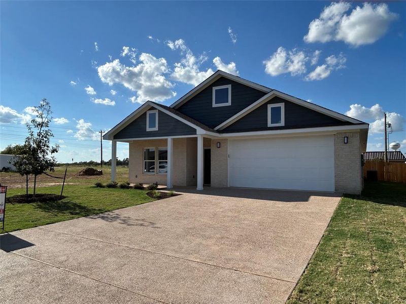 View of front of home featuring brick siding, driveway, and a porch