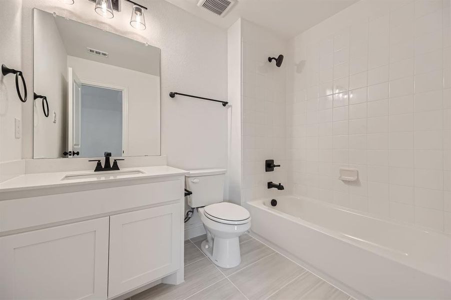 Full bathroom with vanity, tiled shower / bath, and toilet