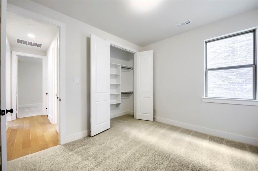 Carpeted room featuring a white interior and a double-door closet with built-in shelving Carpeted room featuring a white interior and a double-door closet with built-in shelving