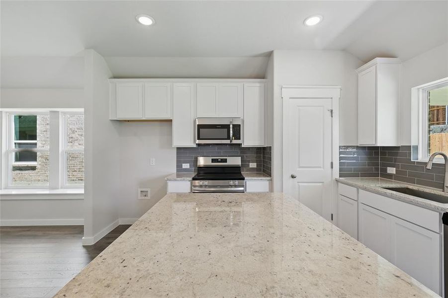 Kitchen featuring appliances with stainless steel finishes, white cabinetry, decorative backsplash, light stone countertops, and recessed lighting Kitchen featuring appliances with stainless steel finishes, white cabinetry, decorative backsplash, light stone countertops, and recessed lighting