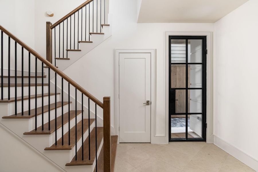 Guests enter through this custom iron-and-glass front door, hidden from the street and covered for inclement weather. A large under-stair closet is great for all kinds of storage. The home is also elevator capable, with a large open closet on each store for climate-controlled storage if you don't add the elevator.