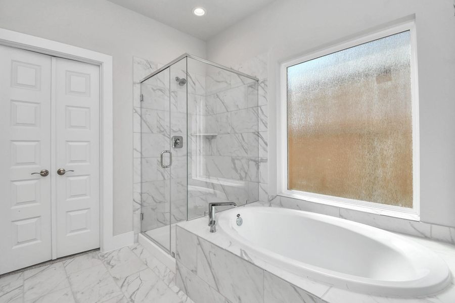 Indulge in a spa-like retreat within the confines of this primary bathroom. Delight in a spacious walk-in shower enveloped in stylish tile surround and unwind in a separate garden tub adorned with custom detailing. Sample photo of completed home with similar floor plan. Actual colors and selections may vary. Indulge in a spa-like retreat within the confines of this primary bathroom. Delight in a spacious walk-in shower enveloped in stylish tile surround and unwind in a separate garden tub adorned with custom detailing. Sample photo of completed home with similar floor plan. Actual colors and selections may vary.