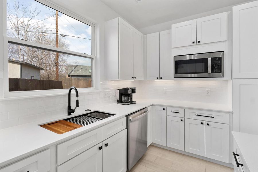 Kitchen featuring white cabinets, stainless steel appliances, and decorative backsplash