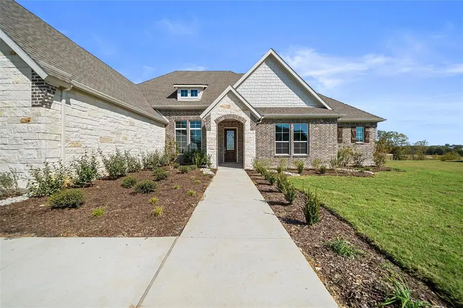 View of front facade featuring a front lawn, roof with shingles, stone siding, and brick siding View of front facade featuring a front lawn, roof with shingles, stone siding, and brick siding