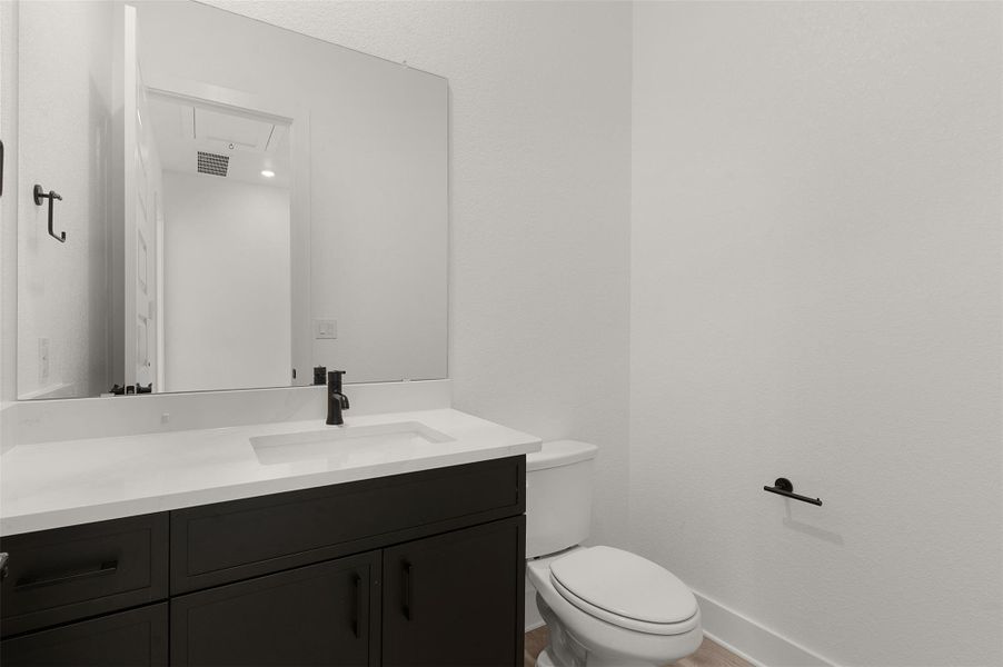 Half bath featuring vanity and toilet Half bath featuring vanity and toilet